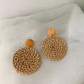 Detailed macro view of bohemian handmade rattan hoop earrings on white linen background - Dark Solid Round