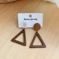 Auffällige geometrische hohle Holzdreieck-Ohrringe mit farbigen runden Steckern auf Karte - Holz Dreieck Stil