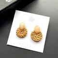 Gedetailleerde macro van bohemian rotan oorbellen met marmeren harsknopjes op kaart - Beige Donker Rotan