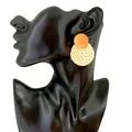 Detail of handmade bohemian woven straw drop earrings on a black display model - Orange Beige Circle Style (A32)