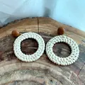 Close-up of handmade woven straw hoop earrings with resin studs on wood background - Brown Stud Woven Circle Style (A130)