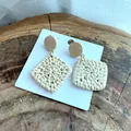 Macro shot of handmade square rattan earrings with wooden studs on a wooden display - Square Wood Woven Style (B41)