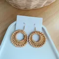 Detail view of Bohemian round woven straw earrings with metal hooks on white display card - Natural Woven Circle Style (B24)