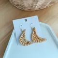 Close-up of handmade crescent woven rattan earrings with golden metal hooks on display - Crescent Woven Style (B23)