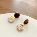 Detailed view of dark wood and woven rattan geometric earrings with golden metallic accents - Light Color Rattan