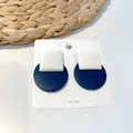 Detail of geometric square and round stud earrings on a white professional card - Square and Round Patchwork Style / Dark Blue