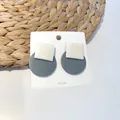 Detail view of geometric square and round stud earrings on a white display card - Square and Round Patchwork Style / Fog Blue