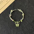 Handmade green woven floral bracelet featuring a translucent star pendant and pink flowers - Clear Green Crystal Star Rope Bracelet
