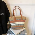 Sac cabas tissé orange et blanc avec anses en cuir marron sur valise argentée - Style Cabas Tissé / Marron