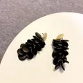 Detail view of tiered long drop earrings with black discs and golden studs - Wood Disc Cluster / Black