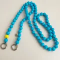 Detail of sky blue beaded strap with a yellow accent bead and silver Love charm - Lake Blue