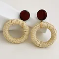 Dettaglio macro di orecchini boho in rattan con borchie in legno su decoro in ceramica - Legno Marrone Scuro - Stile Tondo in Raffia Beige Chiaro (A289)