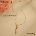 Détail macro du pendentif serpent doré avec zircon rouge sur fond beige texturé - Collier à Long Pompon (NMSN-H436-3)