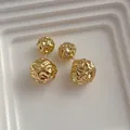 Detail of gold earrings featuring irregular wrinkled double metal spheres on white display - Gold (G171)