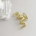 Macro shot of matte gold wave-shaped hair claw clip with spring and non-slip teeth - Gold