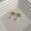 Macro shot of minimalist gold bean stud earrings with screw ball backings on white display - Gold