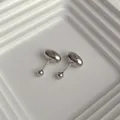Minimalist silver bean stud earrings with screw-back closures on a textured tray - Silver