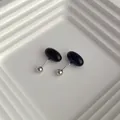 Macro view of black enamel mini oval stud earrings with secure ball screw back closure - Black
