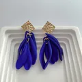 Detailed macro shot of vintage blue resin petal earrings with gold hammered studs - Blue