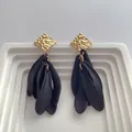 Close-up of hammered gold square stud with matte black resin petal drop earrings - Black
