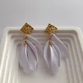 Detail of gold hammered metal stud and white matte resin petal pendant on earrings - White