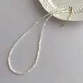 Close-up of white shell bead necklace featuring golden lobster clasp and adjustable chain - White (G278)