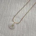 Details einer goldenen Schlangenkette mit weißem Muschelanhänger und goldenem A - Halskette Mit Buchstaben A Anhänger