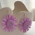 Detailed macro view of purple raffia sunflower earrings with handcrafted woven texture - Purple
