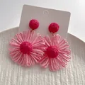Detailopname van de roze raffia bloemoorbellen op een witte displaykaart - Roze