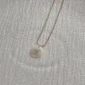 Close-up of golden snake chain necklace with round white shell pendant and letter H detail - Letter H Pendant Necklace