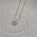 Close-up of golden letter K pendant with iridescent shell inlay on snake chain - Letter K Pendant Necklace