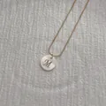 Macro shot of M-letter natural shell pendant with gold snake bone necklace detail - Letter M Pendant Necklace