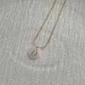 Macro shot of gold snake chain necklace with a white shell pendant featuring the letter O - Letter O Pendant Necklace