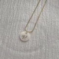 Detail shot of golden snake chain necklace with shell pendant featuring letter V - Letter V Pendant Necklace