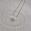 Close-up of golden snake chain with white shell letter W pendant on white texture - Letter W Pendant Necklace