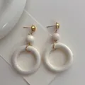 Close-up of minimalist white circular wooden hoop earrings with elegant gold metal studs - White