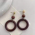 Detail of vintage wooden hoop earrings featuring dark brown wood beads and gold metal studs - Dark Brown