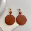 Macro view of retro wooden hoop earrings with warm brown texture and gold studs - Brown Red