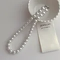 Gros plan d'un élégant collier de perles blanches à un rang avec fermoir argenté - Collier de perles 12mm