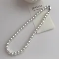 Gros plan d'un collier de perles blanches élégant avec fermoir argenté raffiné - Collier de perles 10mm