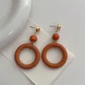 Macro detail of vintage wooden hoop earrings with gold studs and deep orange beads - Brown Red