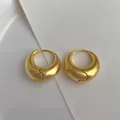 Gros plan de boucles d'oreilles créoles dorées avec texture métal brossé mat - Or Brossé