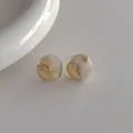 Dettagli ravvicinati di orecchini in resina marmorizzata con bordi dorati irregolari - Beige
