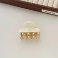 Close-up of cream acetate hair claw clip with golden metal teeth for half-up hair styles - Off White