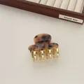 Detail of vintage acetate hair claw with golden metal teeth on a wooden display tray - Leopard Print
