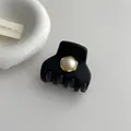 Detail of a matte black claw clip with a gold-trimmed pearl accent on a white background - Beige Pearl Style