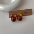Dettaglio di orecchini vintage a goccia in resina ambrata con base in metallo dorato - Marrone
