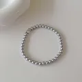 Détail du bracelet en perles argentées orné d'une petite pierre de zircone brillante - Bracelet de perles grises