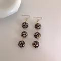 Détail macro de perles en bois léopard sur boucles d'oreilles pendantes avec crochets dorés - Léopard Marron Foncé