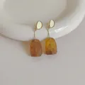 Dettaglio di orecchini vintage in resina ambrata tartarugata e metallo dorato - Ambra